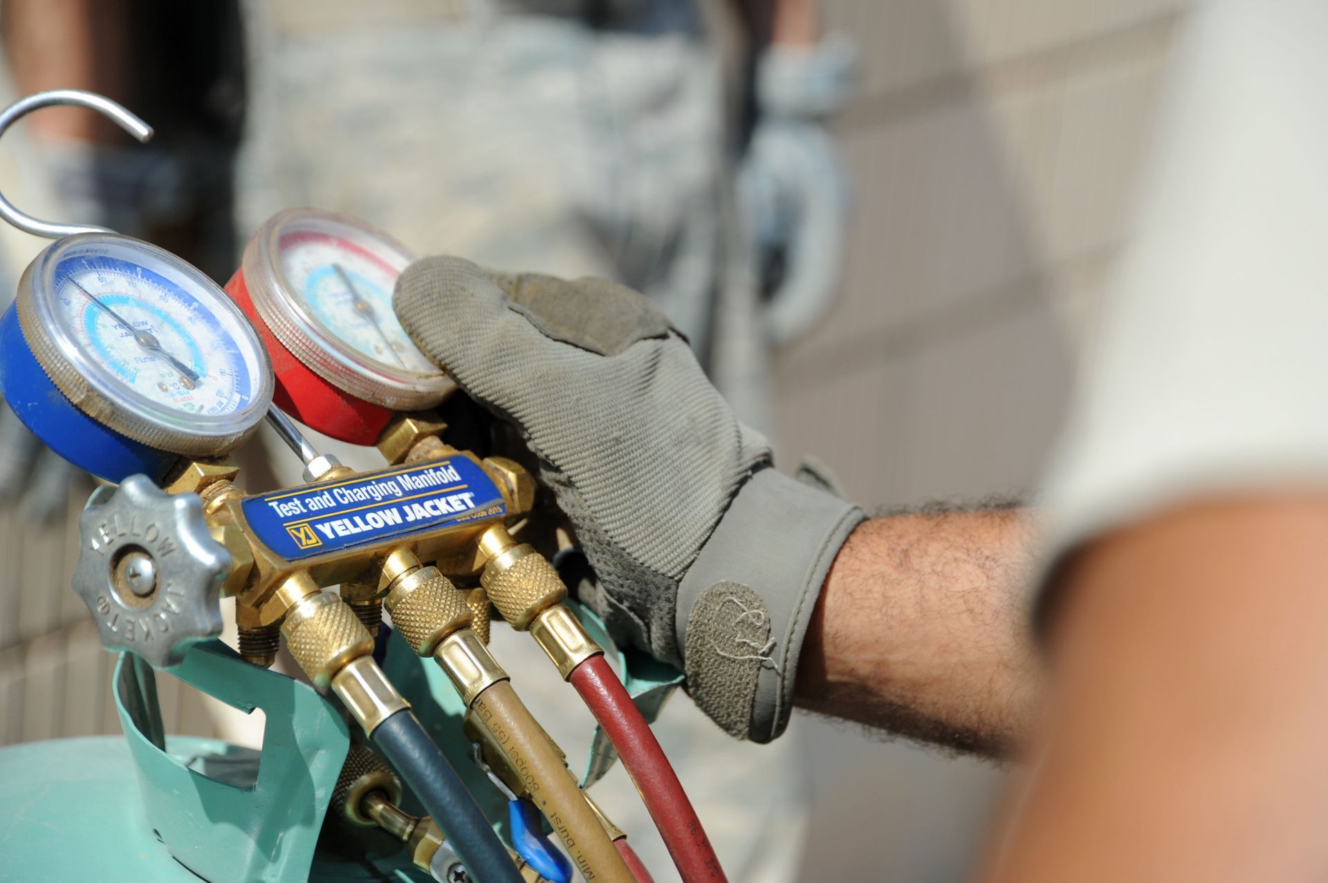 A man wearing a glove is holding a gauge on a machine.