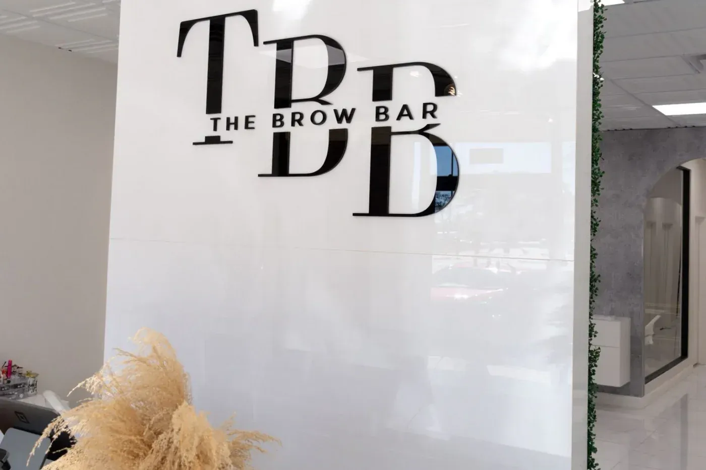 The Brow Bar logo on a white wall in a salon interior