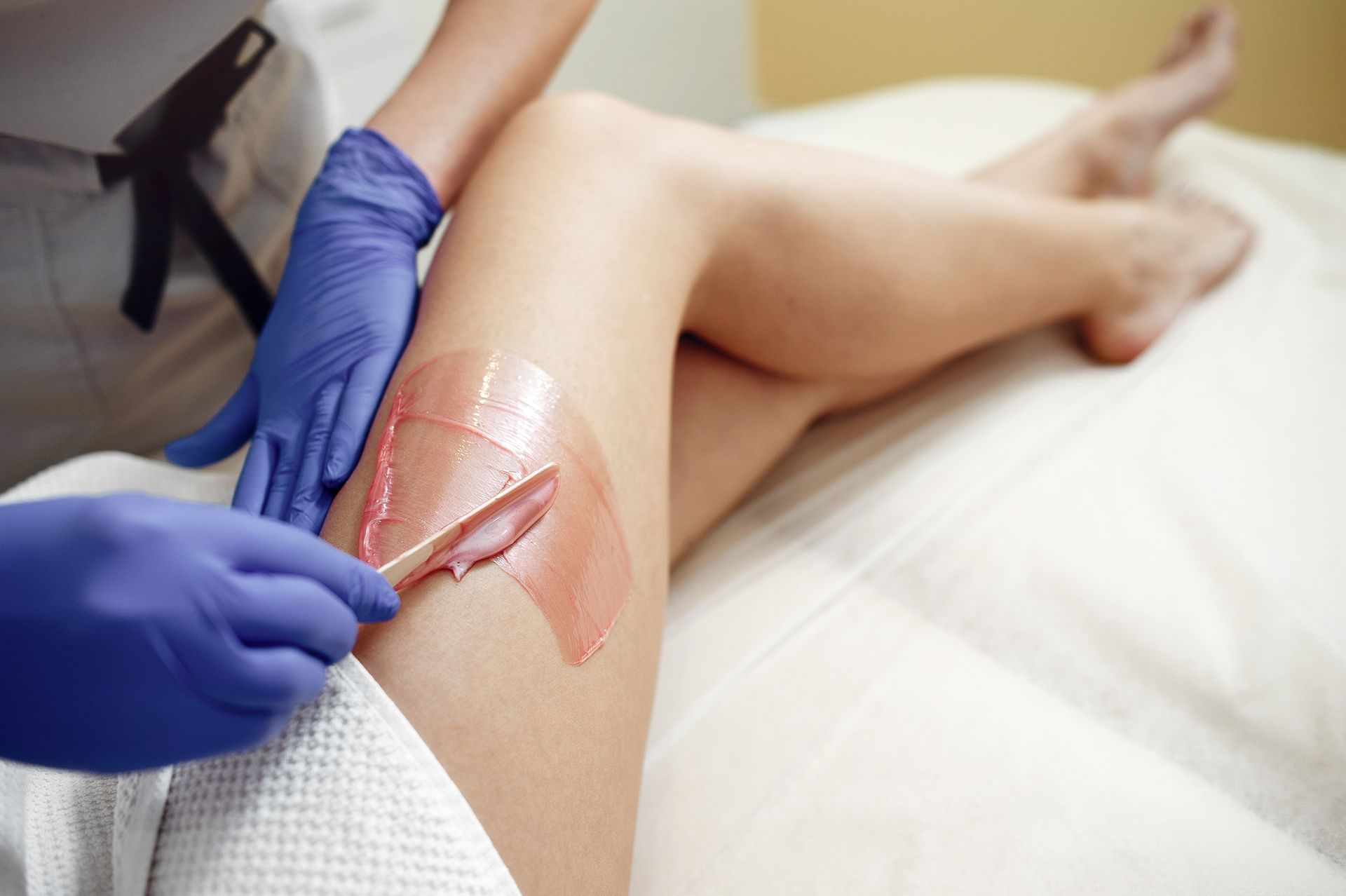 Gloved hands apply ointment and a transparent dressing to a knee wound on a reclining patient