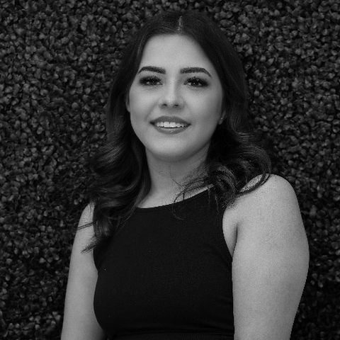 Smiling woman in a black sleeveless top against a textured dark backdrop