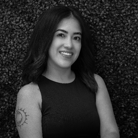 Smiling woman in a black sleeveless top standing before a textured wall