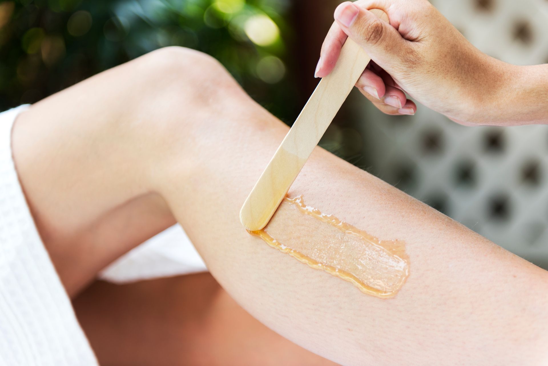 Applying wax to a leg with a wooden spatula during hair removal