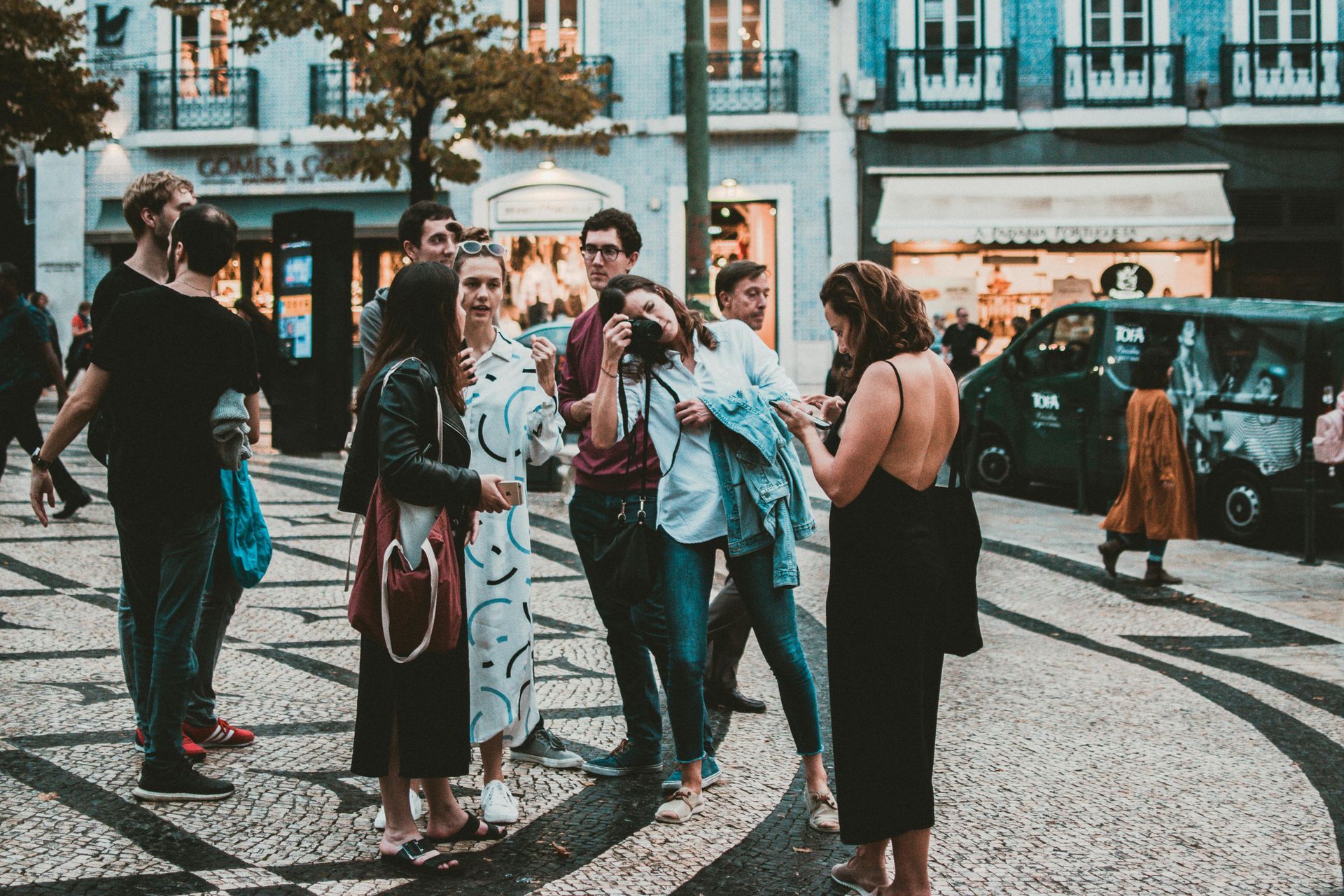 A group of people gathered on a cobblestone street, some laughing, others looking at each other.