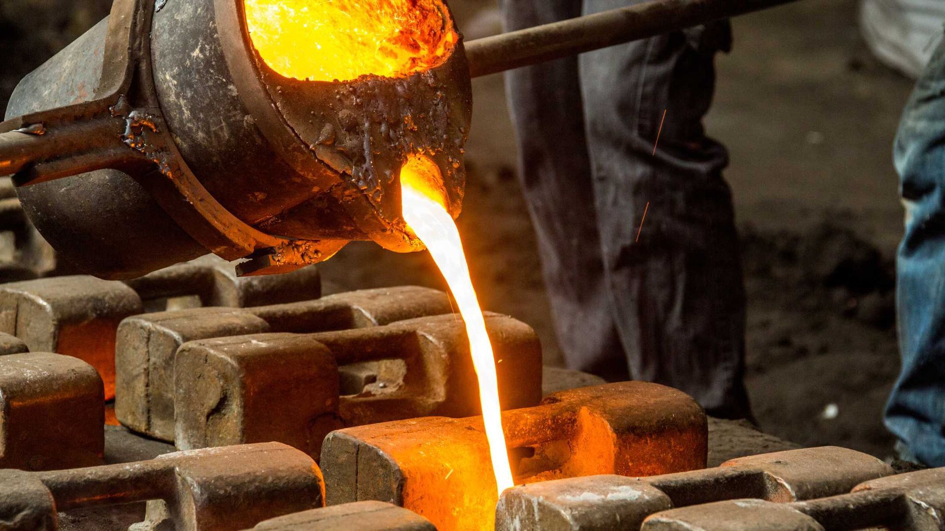 A person is pouring molten metal into a furnace.