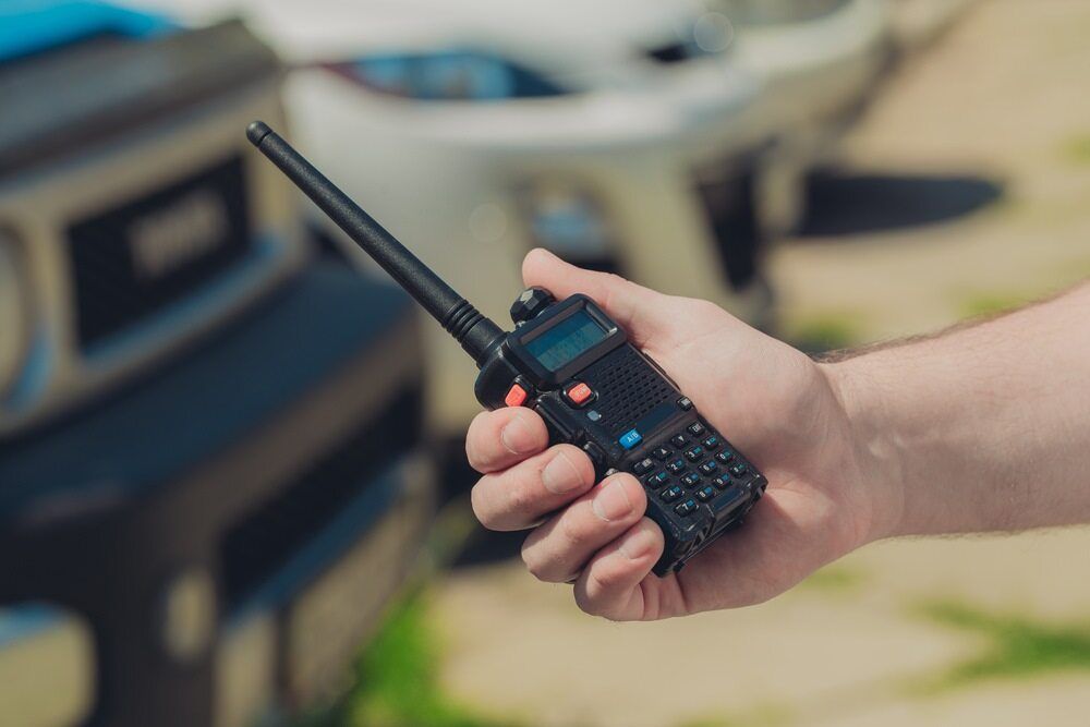 A Person Is Holding A Walkie Talkie In Front Of A Car — Bradshaws Radio & TV Service In Maryborough, QLD