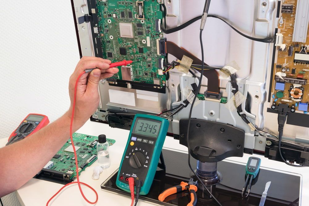 A Person Is Working On A Television With A Multimeter — Bradshaws Radio & TV Service In Maryborough, QLD