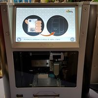 Primo piano di una stampante 3D con display touchscreen e camera di stampa aperta