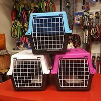 Tre trasportini colorati per animali impilati su un tavolo rosso in esposizione in un negozio.