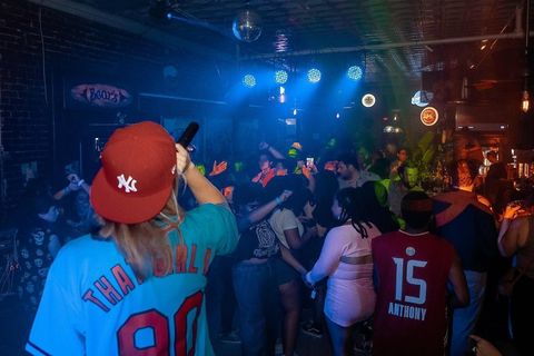 Crowded nightclub with blue lights, people dancing, and fans wearing sports jerseys and caps