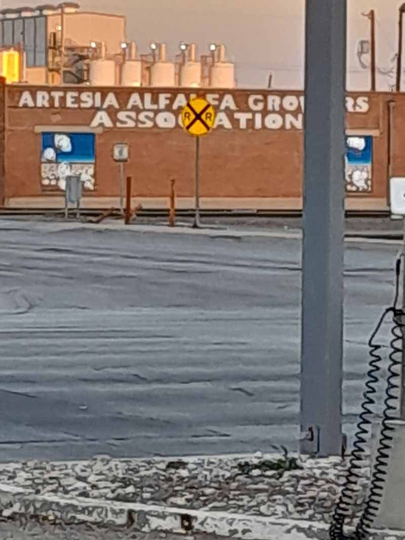 A railroad crossing sign in front of a brick building with 