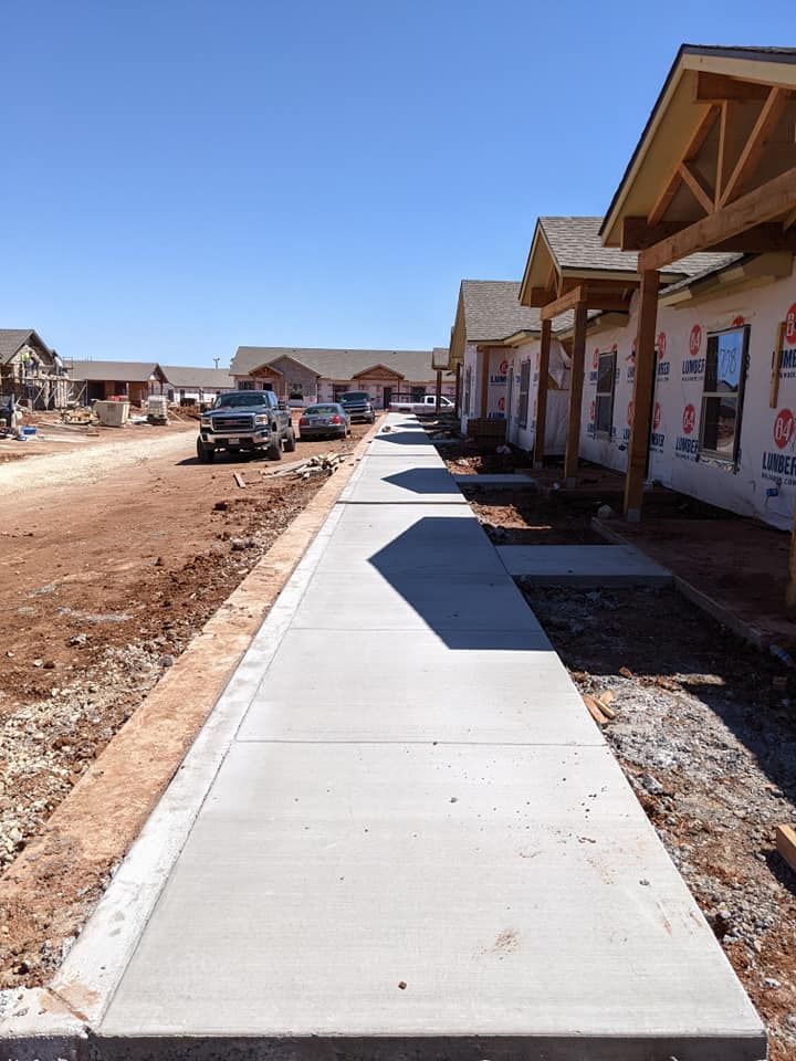Sidewalk under construction next to newly built houses on a sunny day.