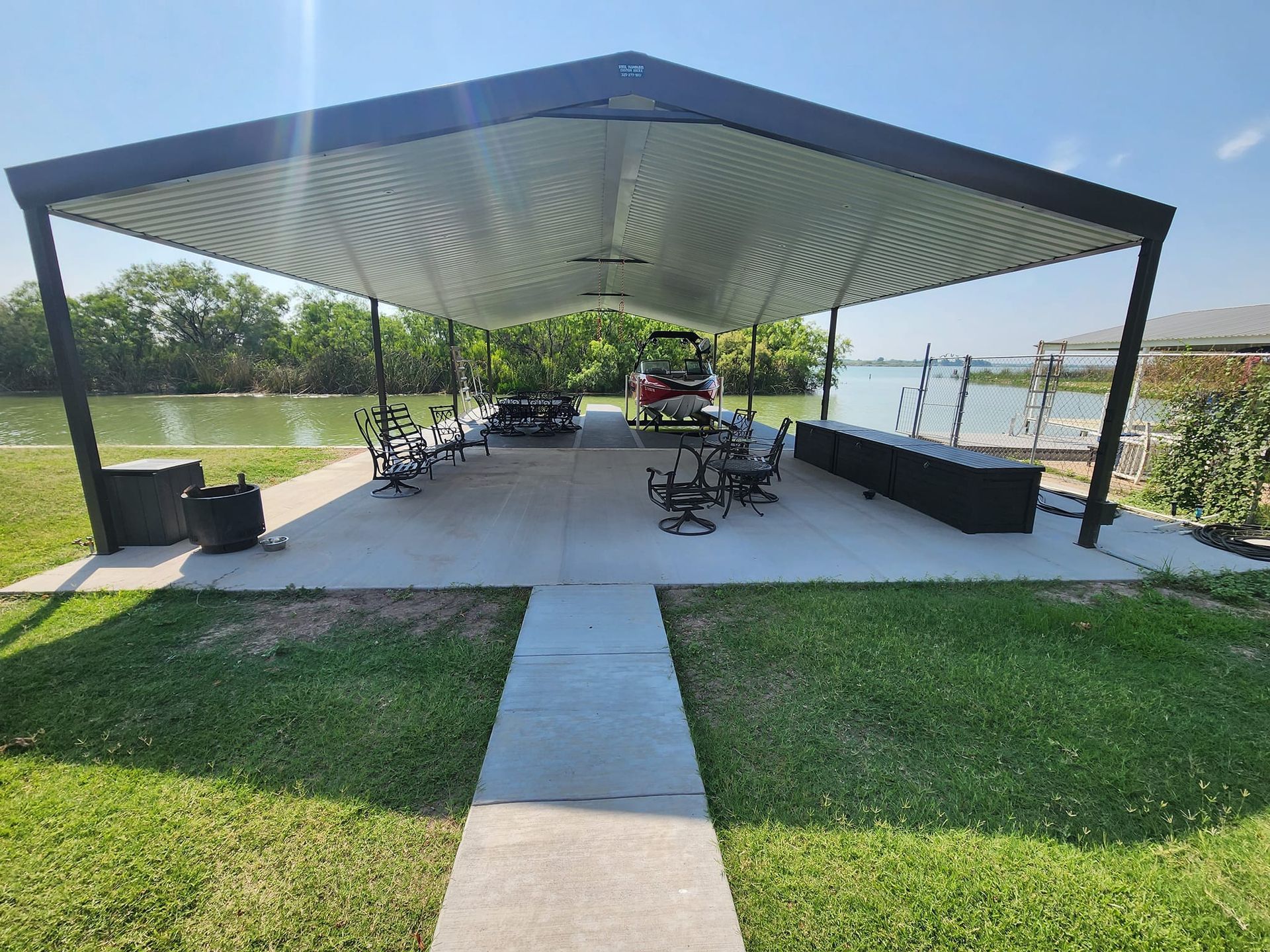 Covered dock with workout equipment overlooking a body of water, grass in the foreground.