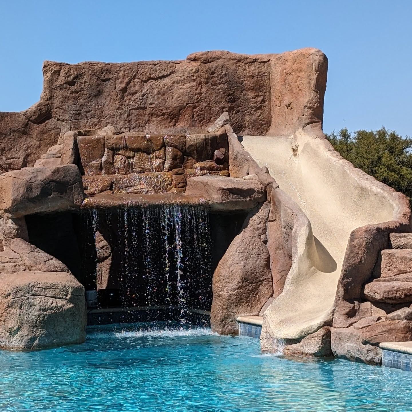 Pool with rock waterfall and water slide.