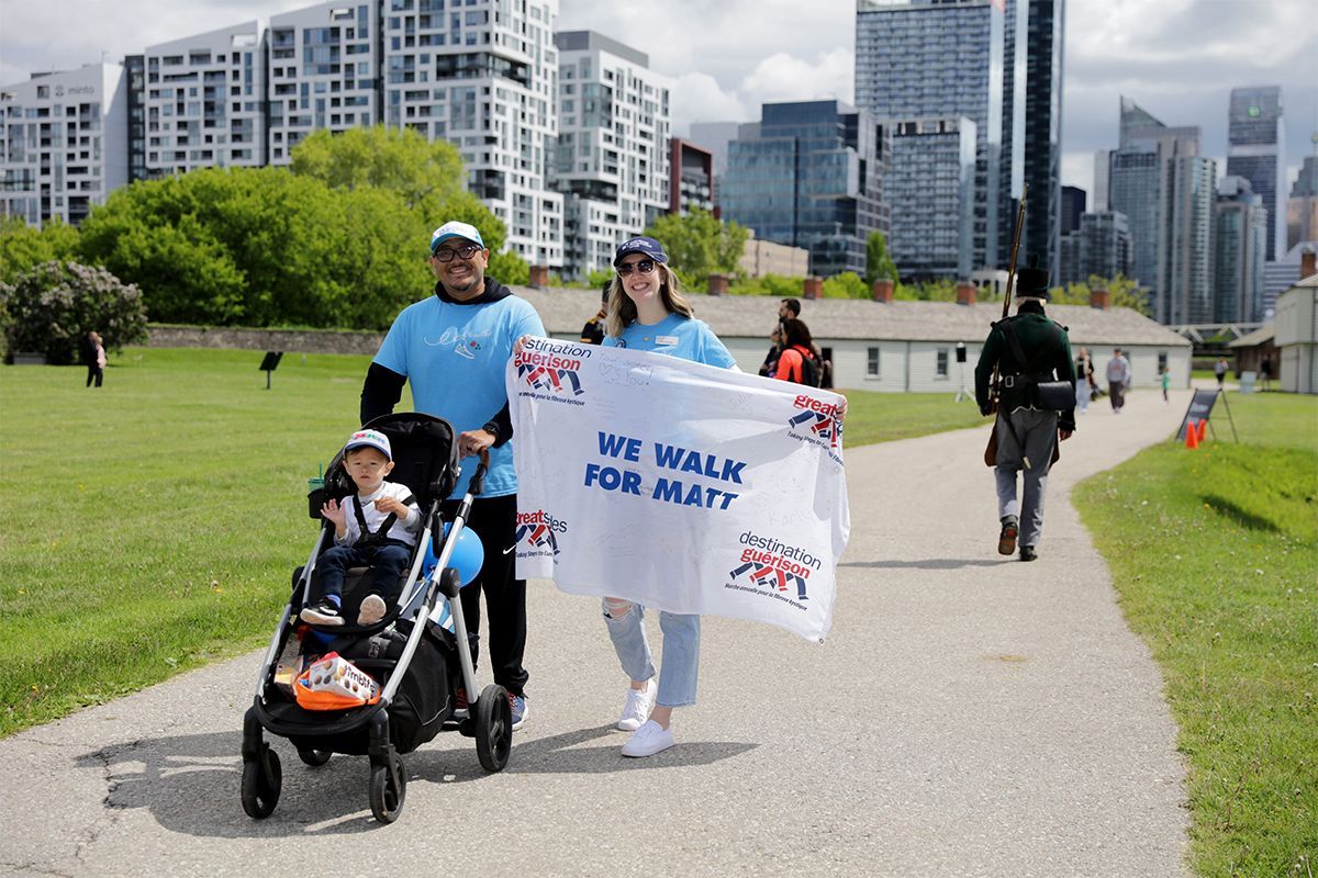 A young family walk the event path with a banner that reads, 