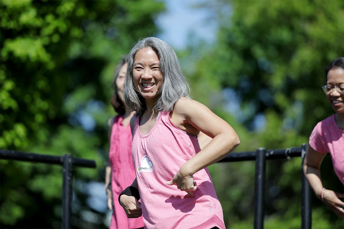 A middle aged asian woman is smiling brightly at The Walk to Make Cystic Fibrosis History.