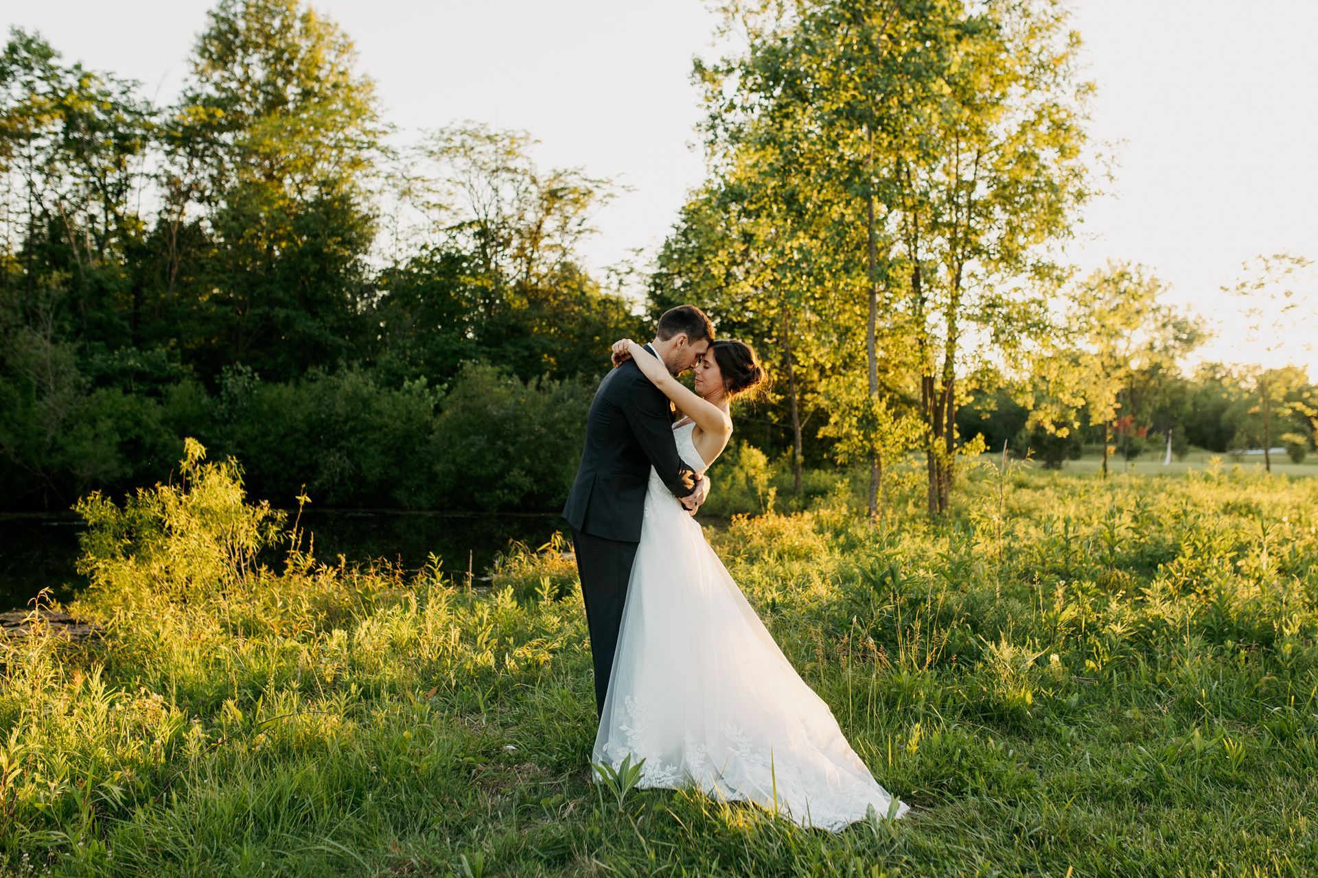 Young couple recently married hugging surrounded by greenery at sundown