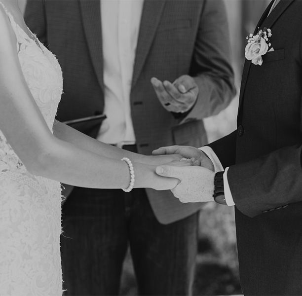 A black and white photo of a bride and groom holding hands