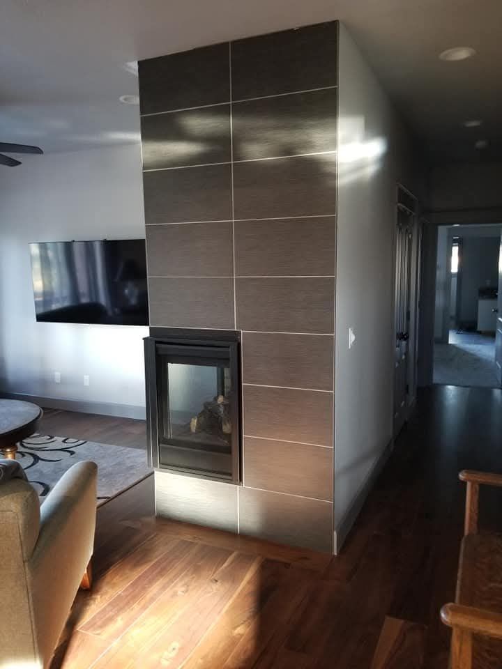 Modern fireplace with dark gray tiles, recessed fireplace, wood floor, and hallway entrance.