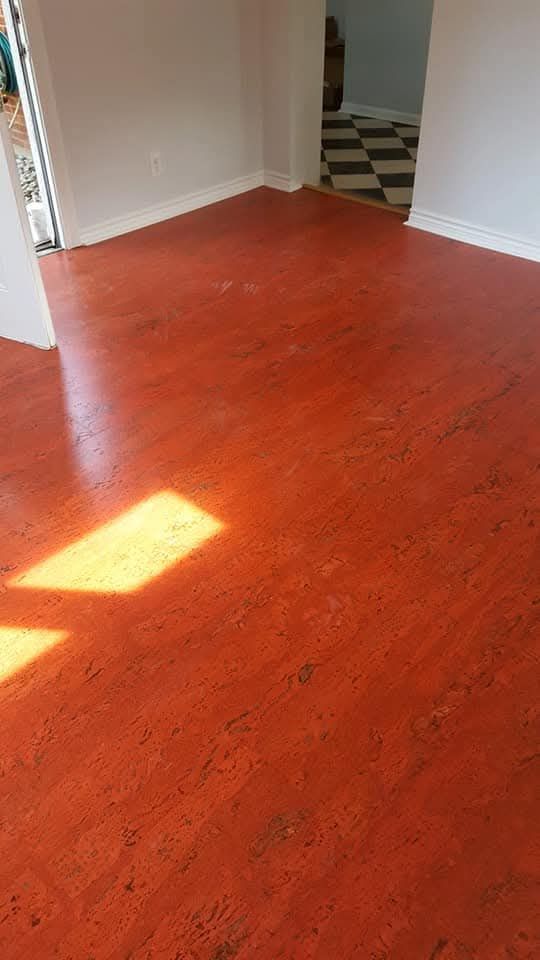 Person installing wood flooring, measuring with a tape measure.
