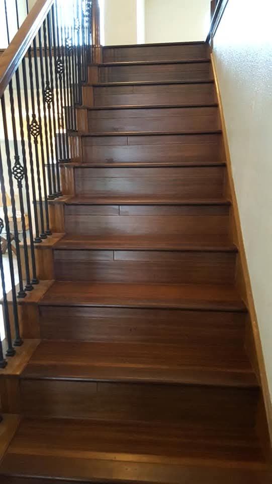 Wooden staircase with wrought iron railing. The steps are a dark brown color.