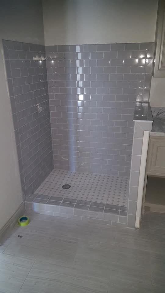 Gray tiled shower stall under construction.