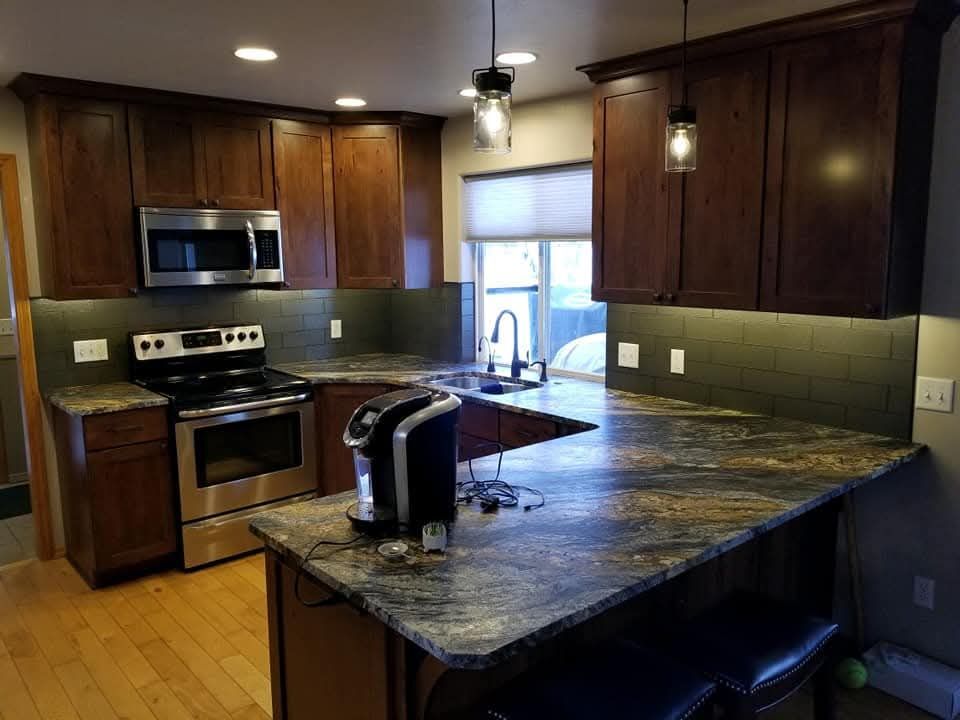 Kitchen with dark brown cabinets, granite countertops, stainless steel appliances, and pendant lights.