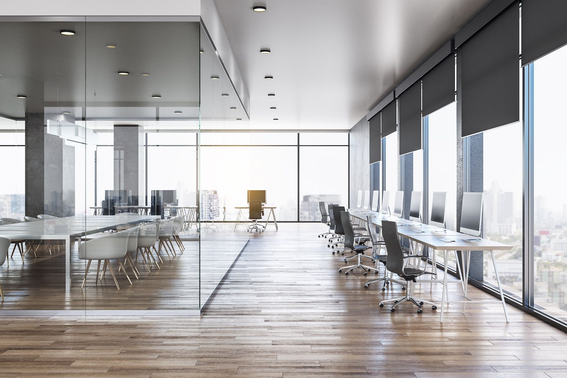 A modern office interior featuring a glass-walled conference room and a long row of computer workstations by a window.