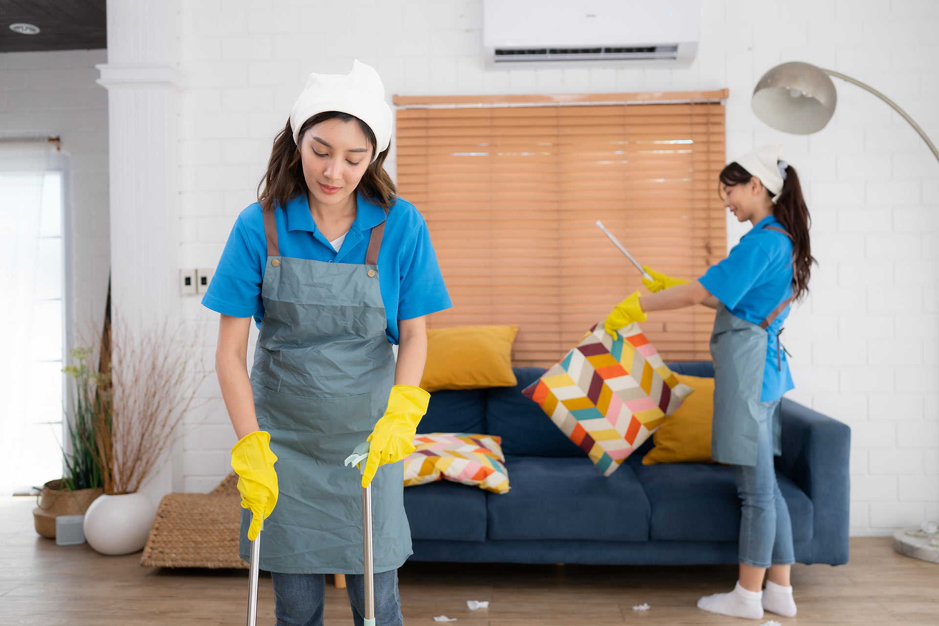 Two women are cleaning a living room in a house.