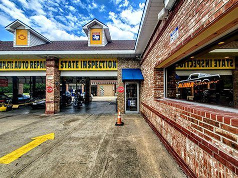 Brick auto repair shop entrance with state inspection signs and a concrete driveway