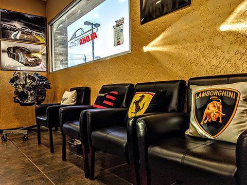 Luxury car showroom lounge with black chairs and Lamborghini-branded cushions along a gold wall