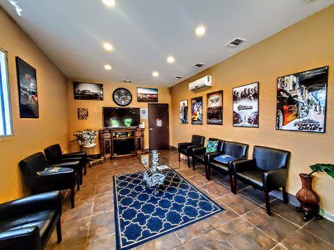 Modern waiting room with black chairs, blue rug, warm tan walls, and framed artwork.