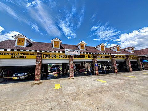Automotive battery and charger shop strip mall with open bays under a blue sky