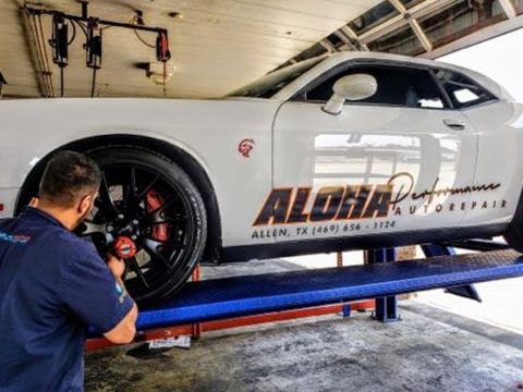 Mechanic working on a white sports car on a lift in an auto shop