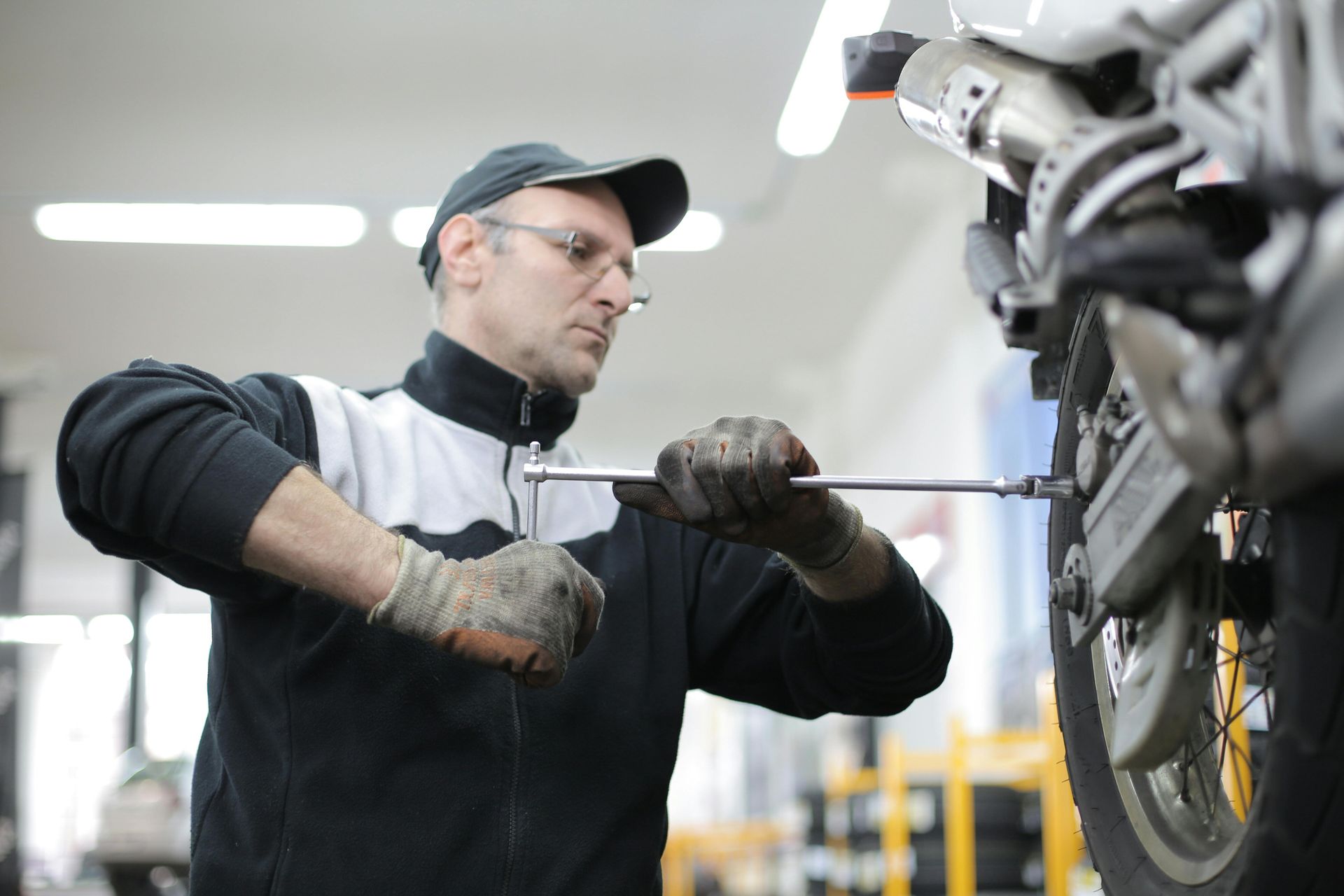 Mechanic in black workwear tightening a motorcycle part in a garage