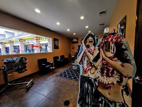Two costumed performers in a tattoo shop lobby with dark chairs, wall art, and a window to the street.