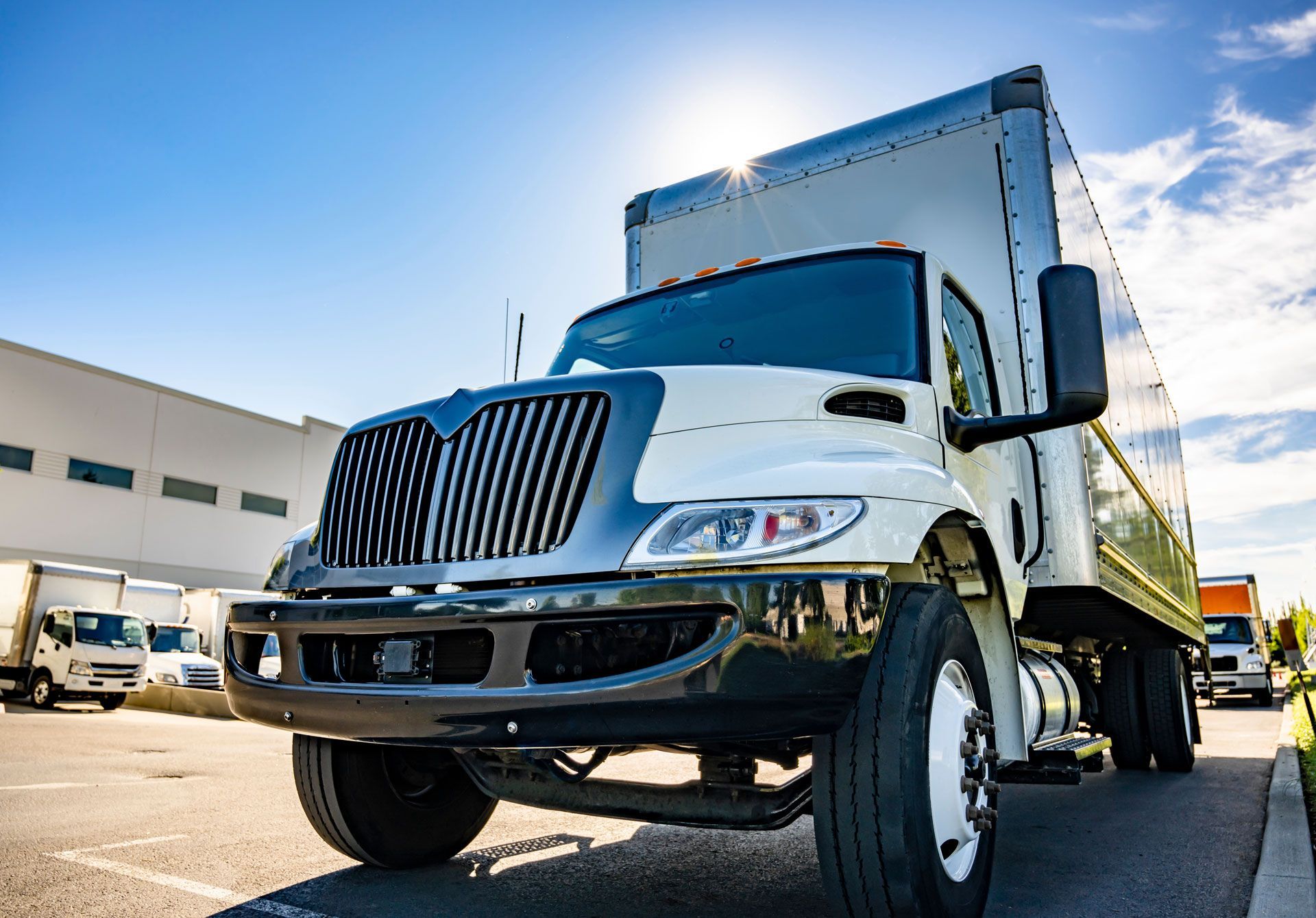 White delivery truck parked outside a warehouse on a sunny day
