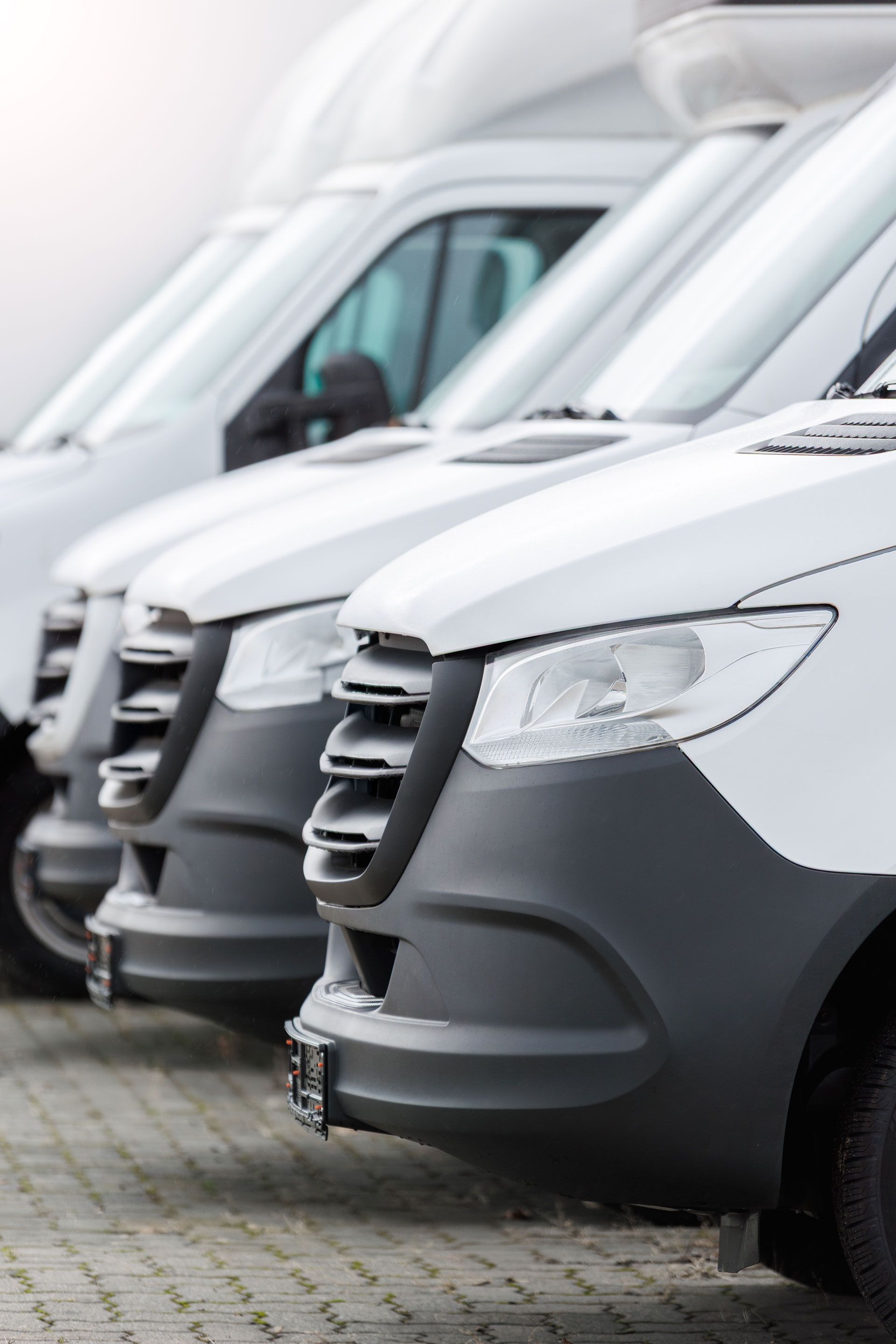 Row of white delivery vans parked closely together in a lot