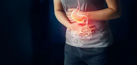 Person holding stomach with glowing digestive system overlay, suggesting abdominal pain
