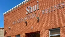 Brick storefront with “Shui” sign and blue sky