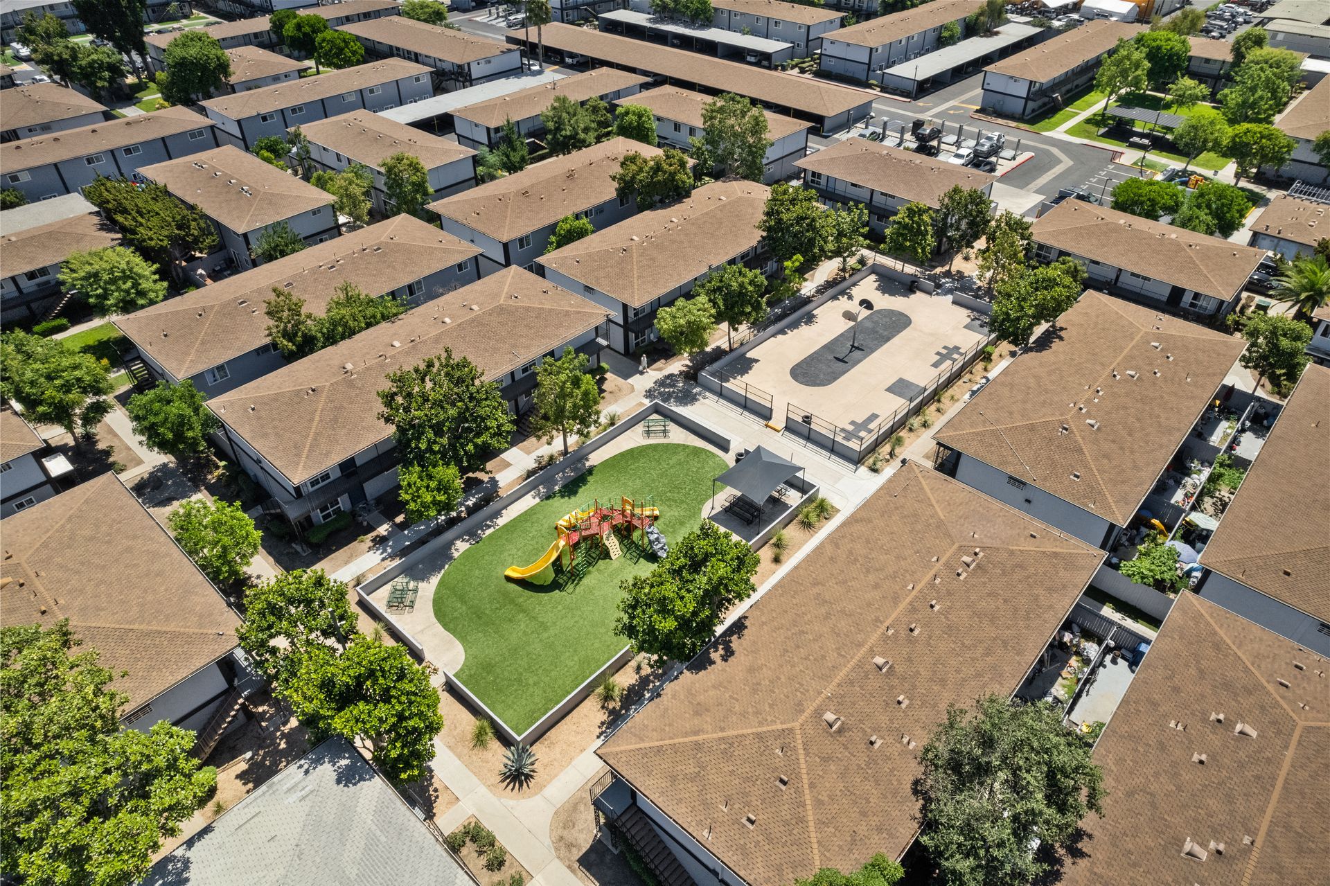 Drone photo of playground and basketball court surrounded by apartments 