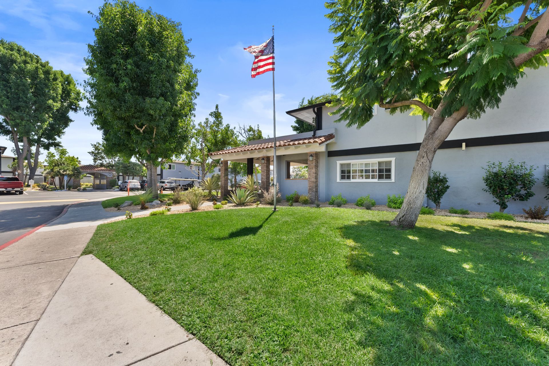 Grass and tree in front of the leasing office with American Flag waving 