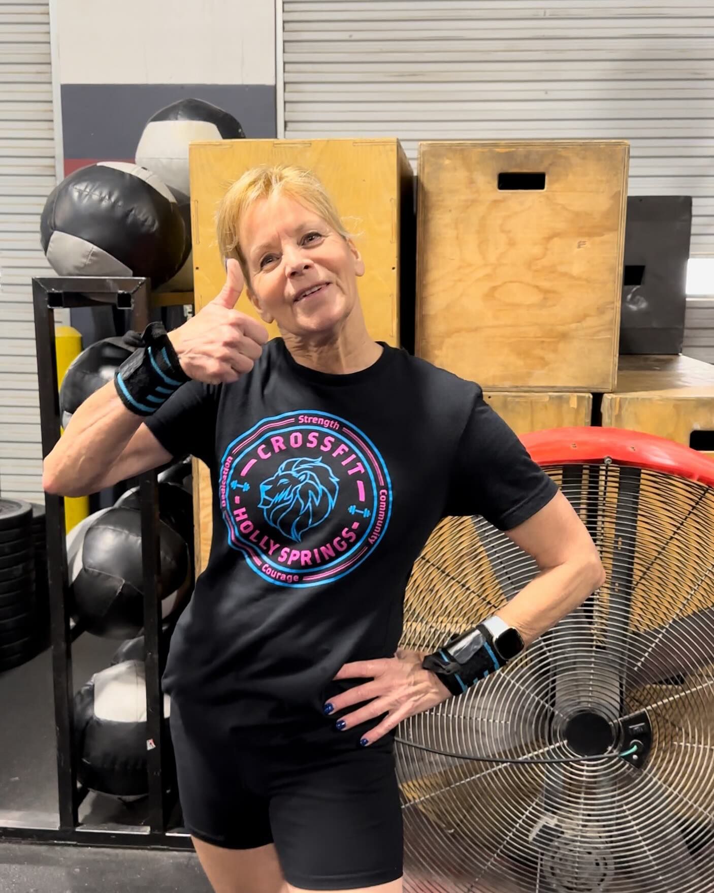 A woman is giving a thumbs up in a gym.