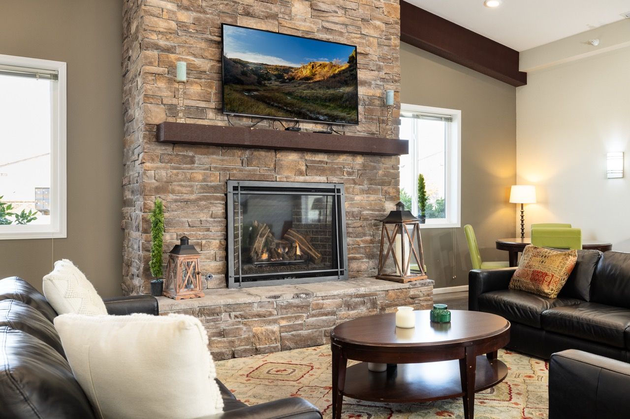 Living room with a stone fireplace, mounted TV, and leather sofas.
