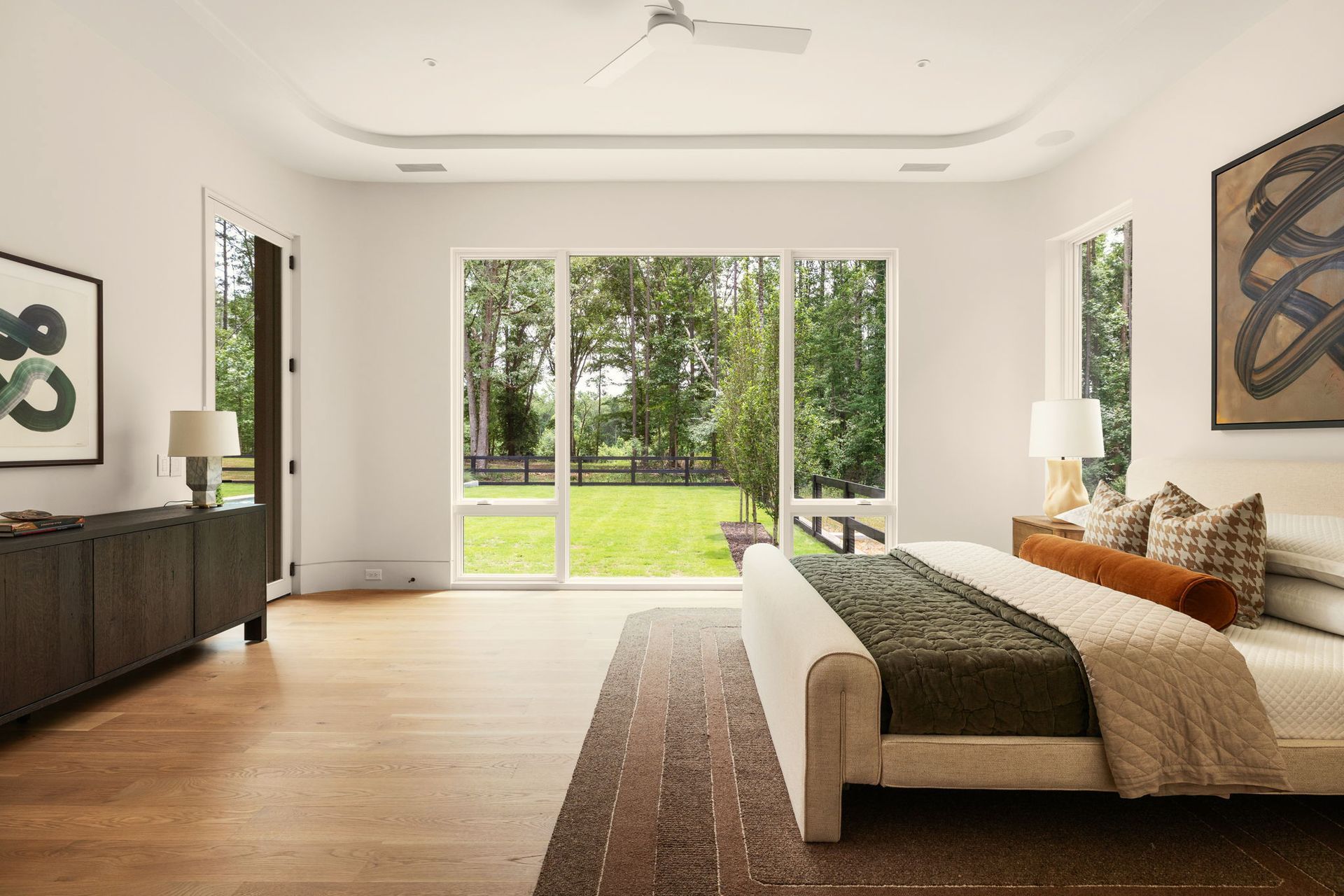 Primary bedroom with green quilted bedding and floor-to-ceiling windows