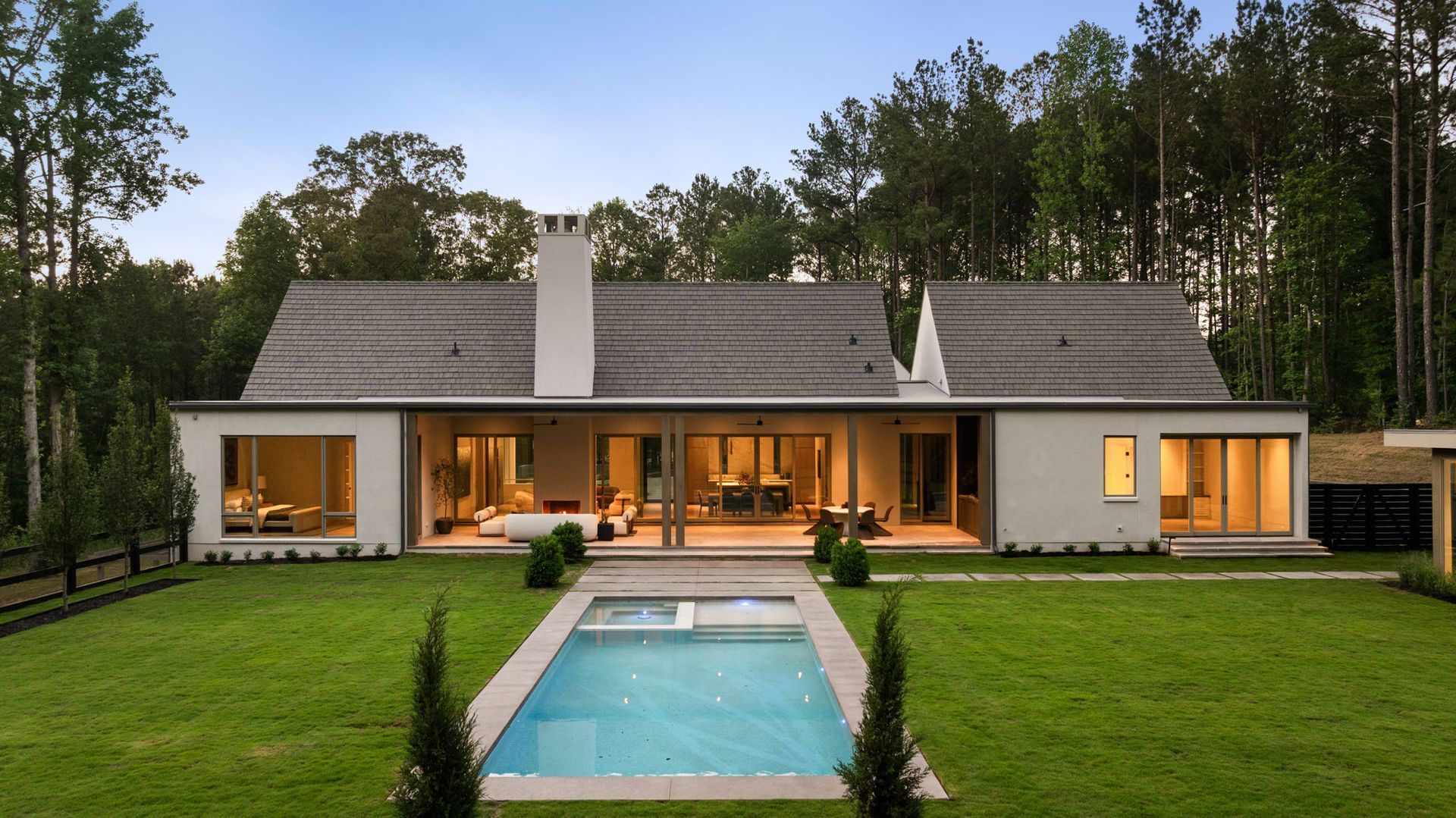 Rear elevation of estate at dusk with pool and covered porch