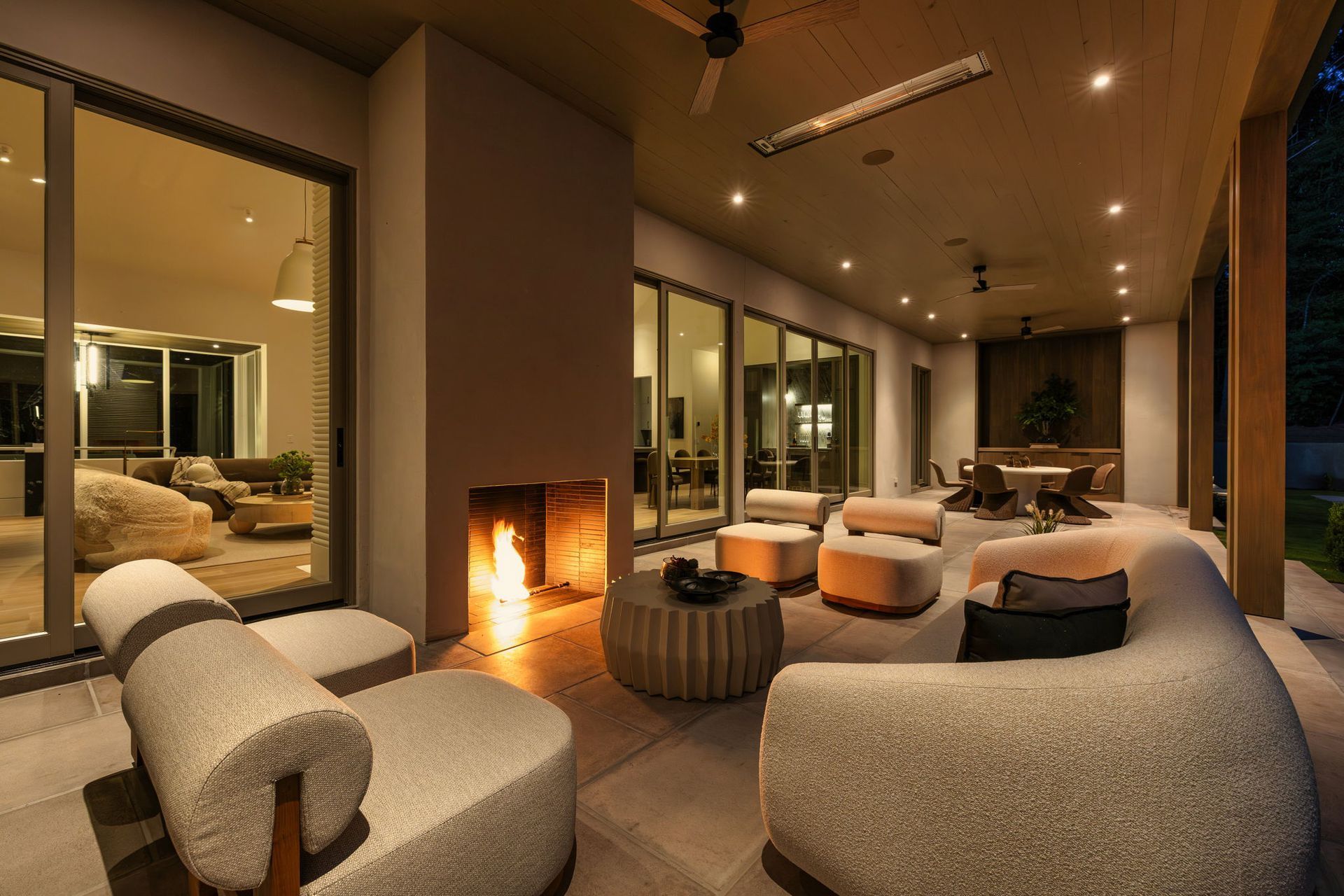 Outdoor loggia at night with fireplace and plush seating