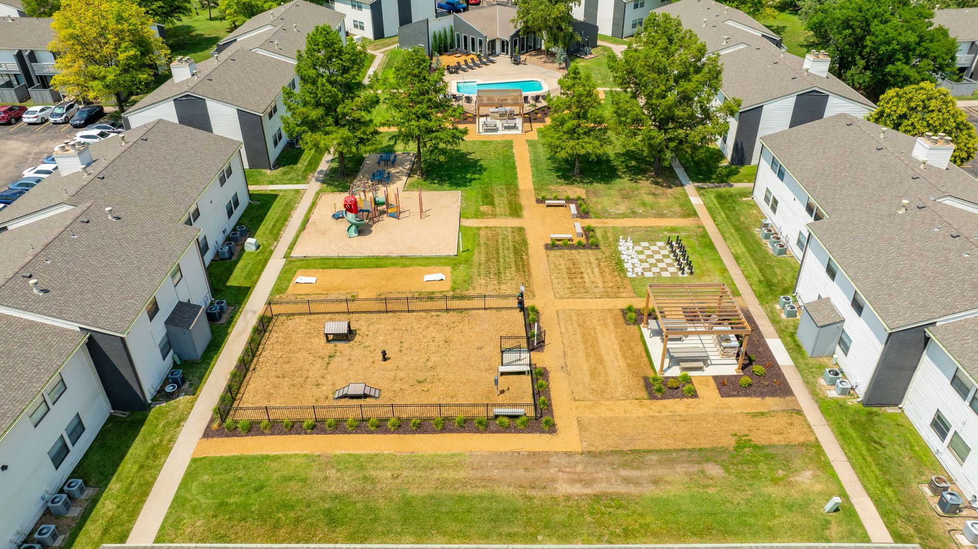 Aerial view of apartment complex with pool, playground, and common areas.