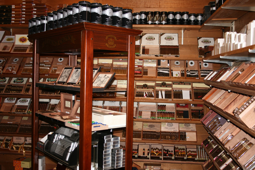 Interior of a cigar shop with wooden shelves and display cases stocked with cigars and accessories