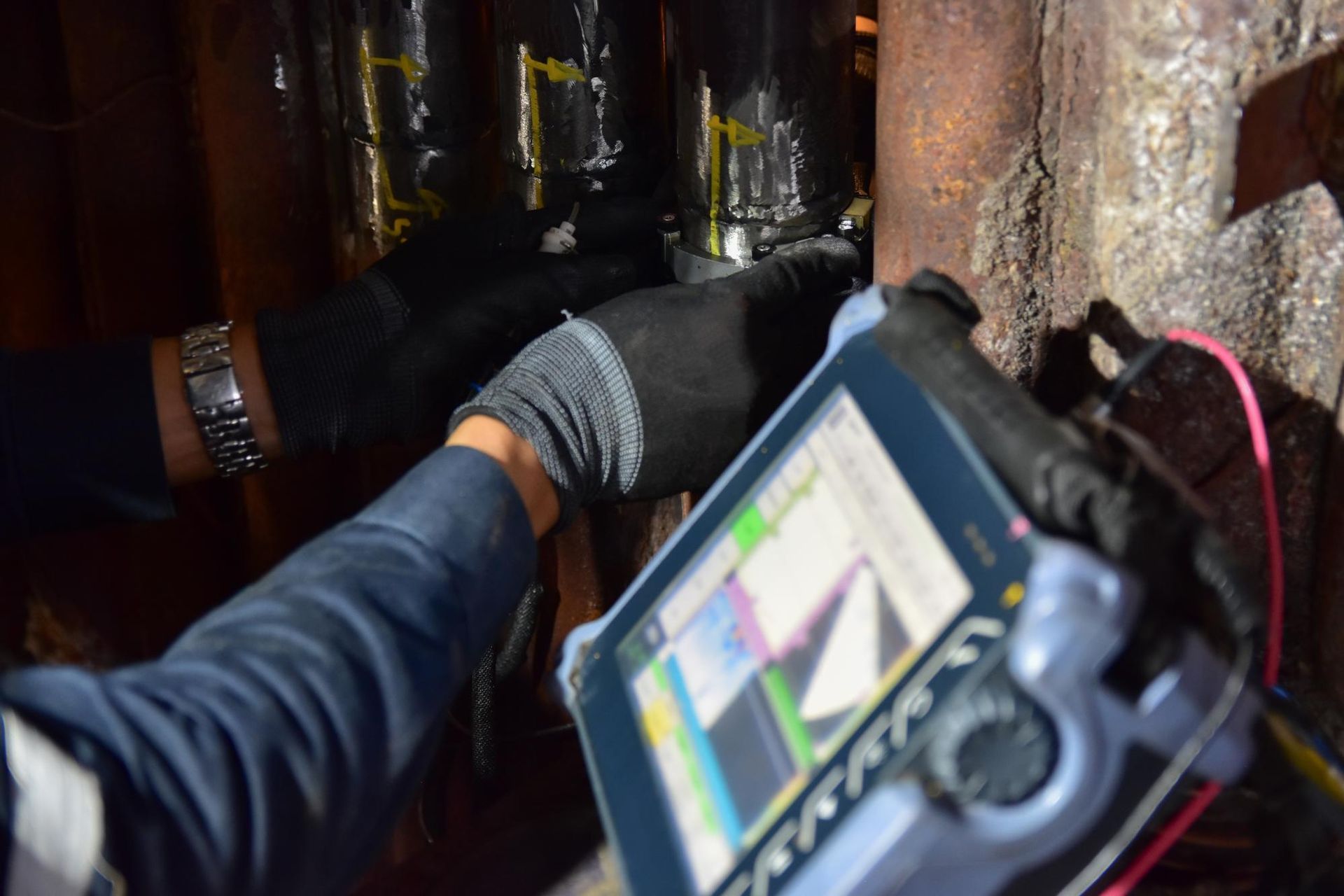 A Person Is Using A Tablet To Inspect A Pipe — LJ's Technical Services In Burdell, QLD