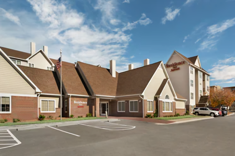 Residence Inn hotel building with brown roof, beige siding, and parking area.